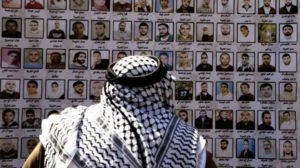 A man looks at pictures of Palestinian prisoners held in Israeli jails during a rally for the release of Palestinian inmates in East al-Quds. (Press TV)