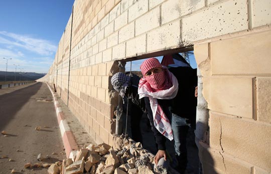 Palestinian-youths-appear-through-a-hole-they-dug-in-the-controversial-Israeli-separation-wall-in-the