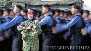Royal Brunei Navy personnel marching in unison, while a RBAF personnel stands guard at the Defence Academy.