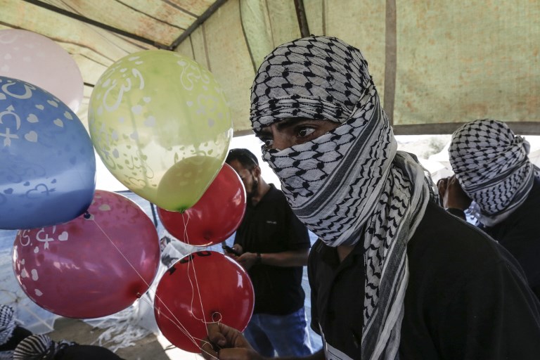 Masked Palestinians prepare balloons loaded with flammable material to be flown toward Israel,