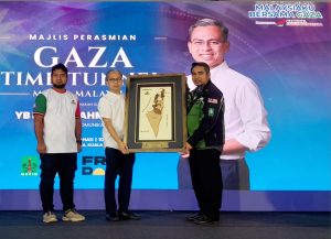 Malaysian Communications Minister Datuk Fahmi Fadzil (center) receives a souvenir at the inauguration of the Gaza Time-Tunnel Humanitarian Virtual Reality (VR) Innovation Exhibition during the Sumud Nusantara Carnival at Dataran Merdeka, Kuala Lumpur, Sunday (August 24, 2025). (Photo: Rana/MINA)